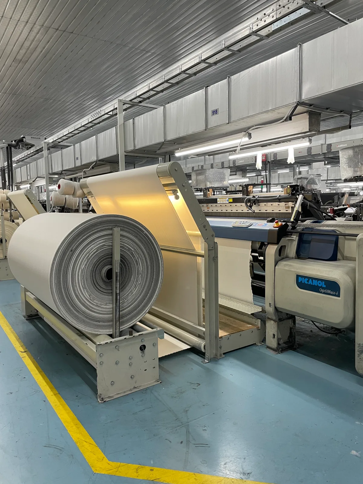 Aus diesen entsteht bei ISA Sallmann in Amriswil der RCO100-Stoff. RCO100 steht für zu 100 Prozent rezyklierte Baumwolle (englisch Cotton). Produktion von Recycling-Baumwolle im Säntis-Werk in der Südtürkei. Man sieht grosse Trommeln mit Baumwollgewebe.